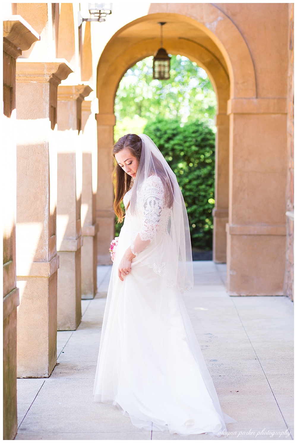 bride looking down as she fixes her dress in under arches at club at corazon