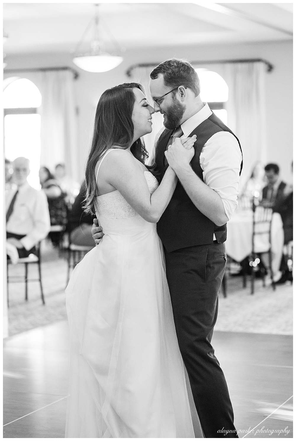 black and white image of bride and groom smiling at each other during first dance