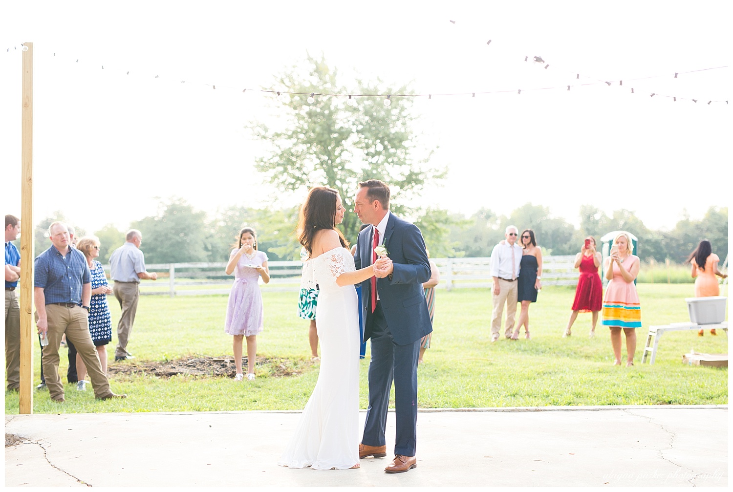 bride and groom having first dance outside under bistro lights