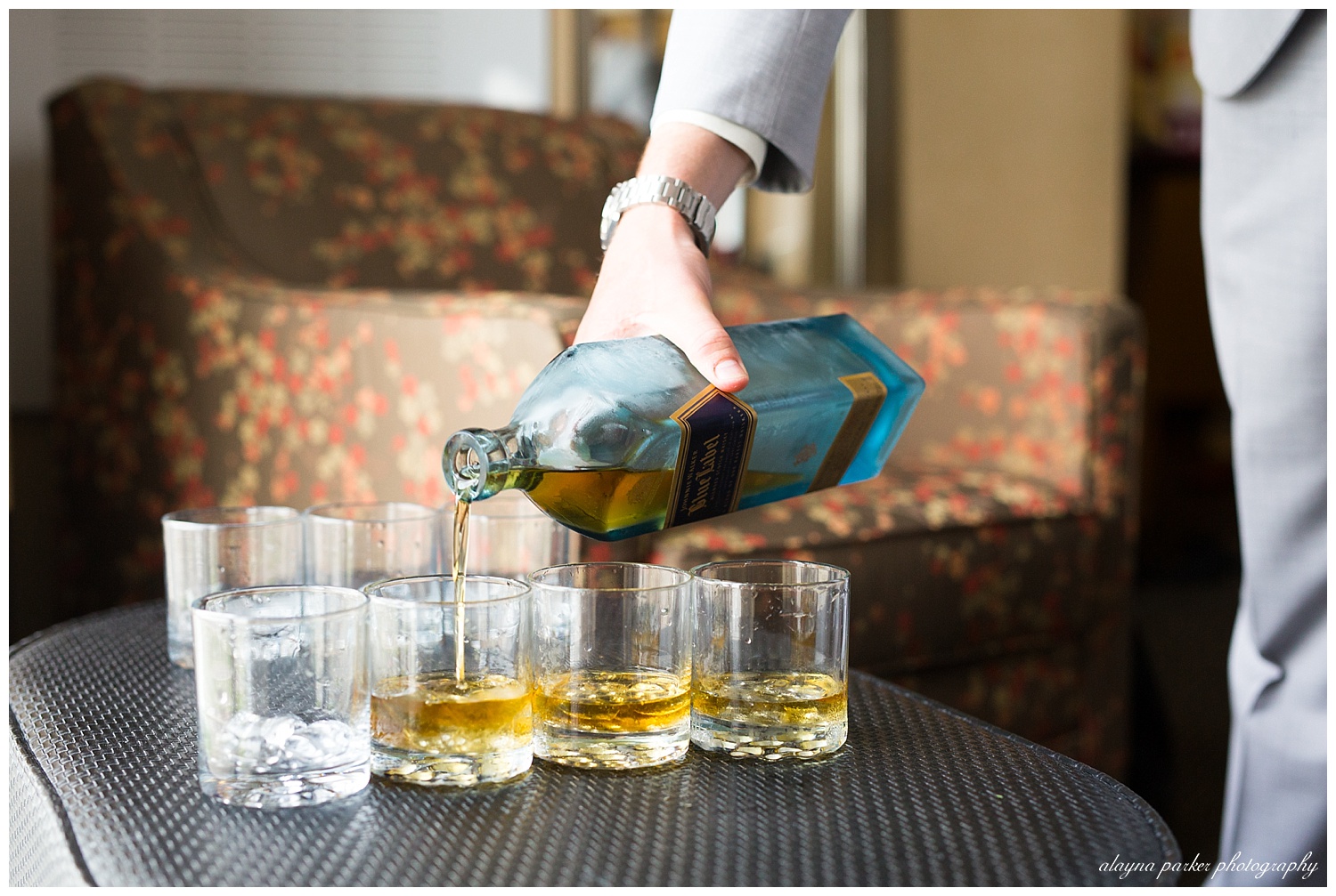 close up of groom pouring whiskey into glasses