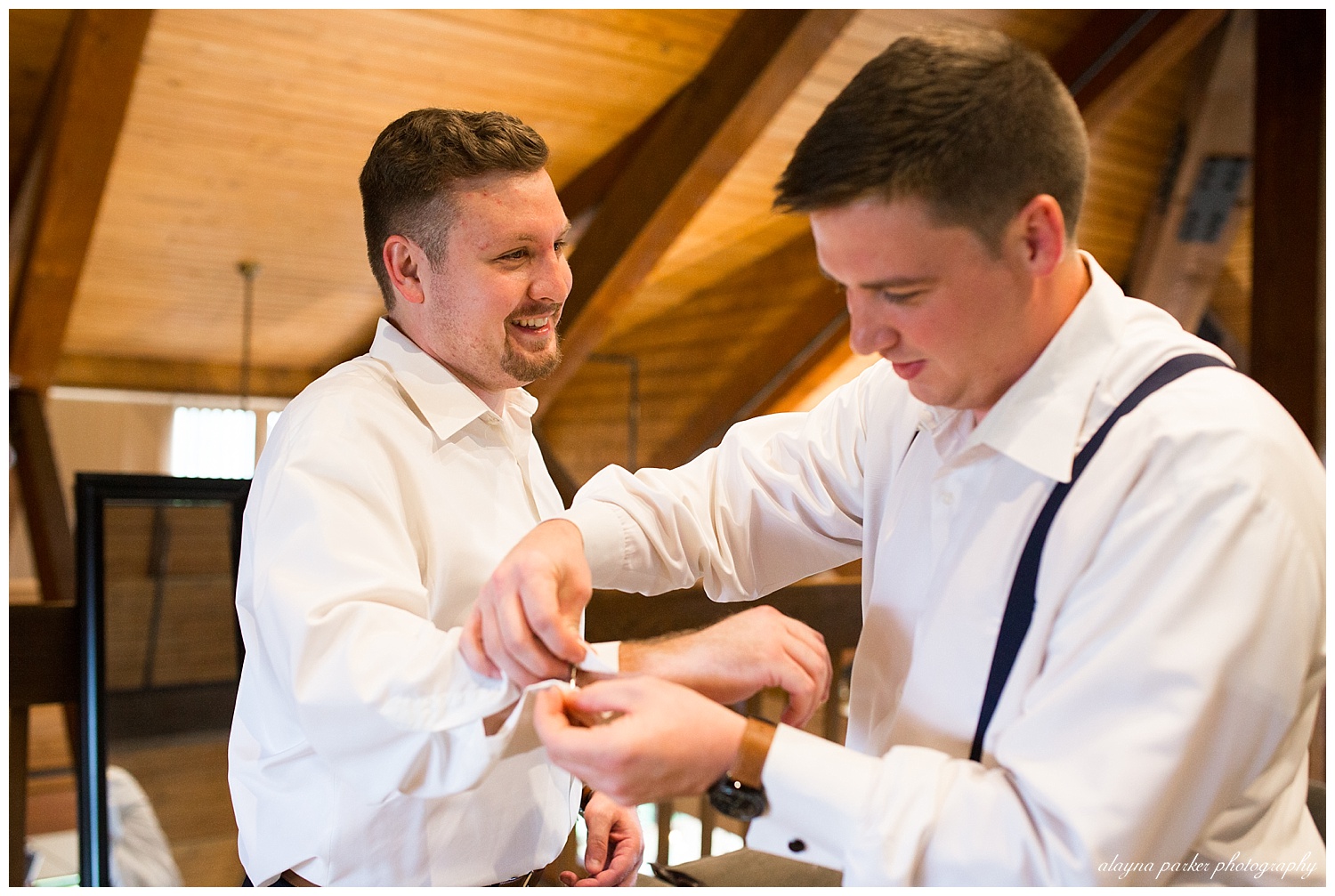 groomsman putting cufflinks on groom