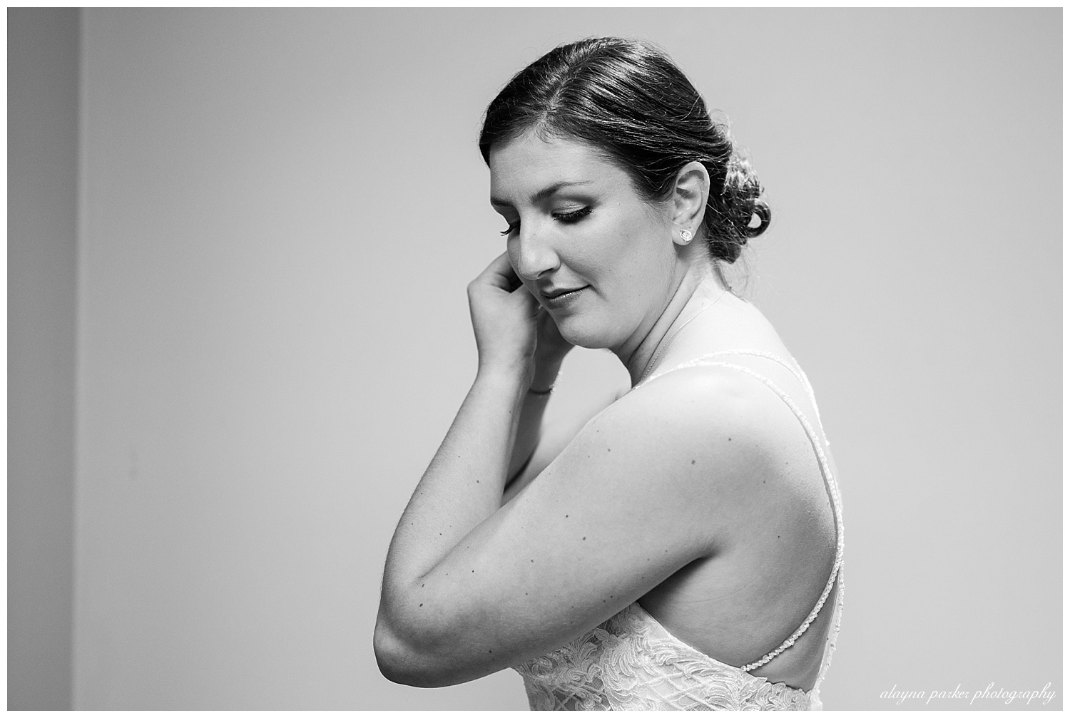 black and white image of bride putting in earrings