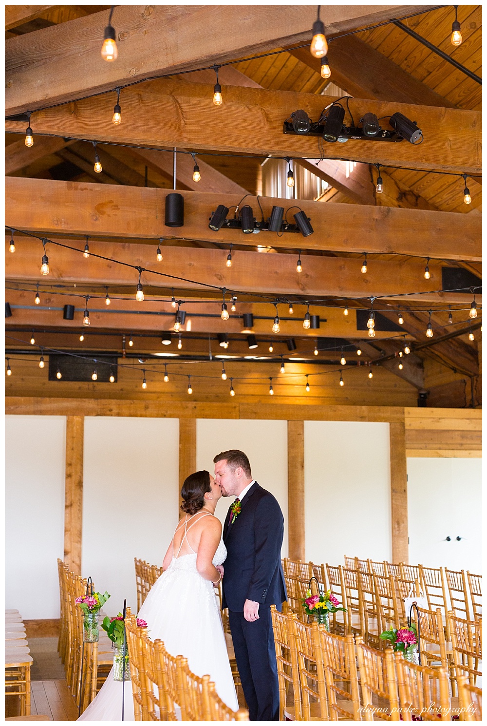 bride and groom kiss in empty ceremony space at water's edge
