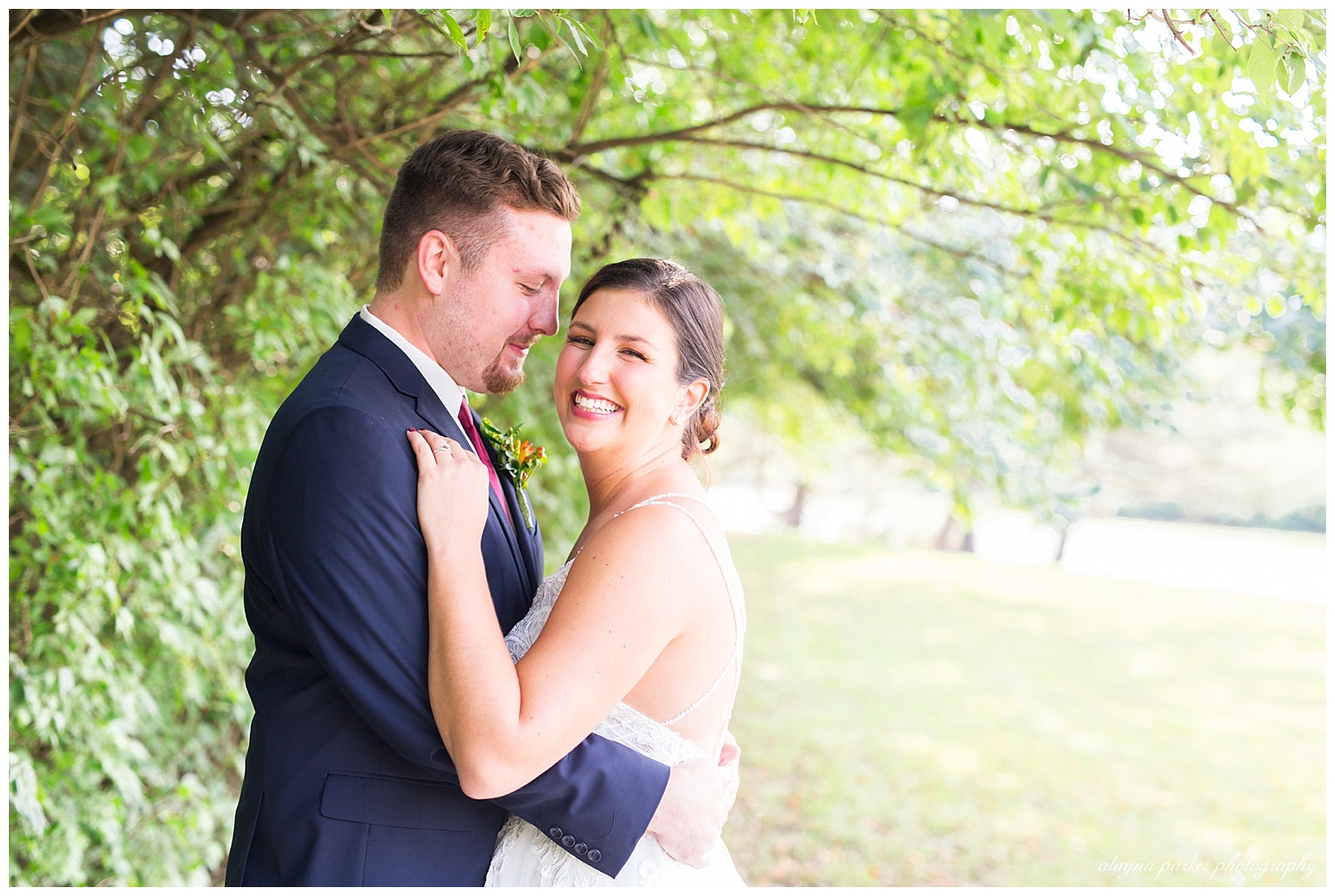 bride laughing at camera while groom smiles at bride at water's edge