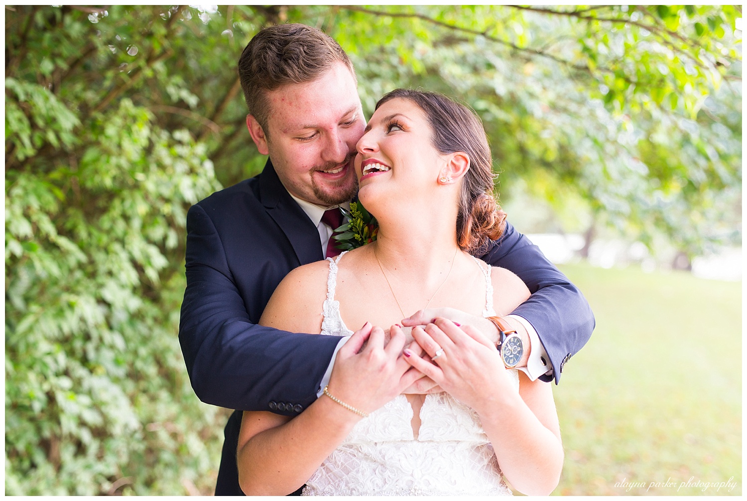 groom wrapping up bride in his arms outside at water's edge