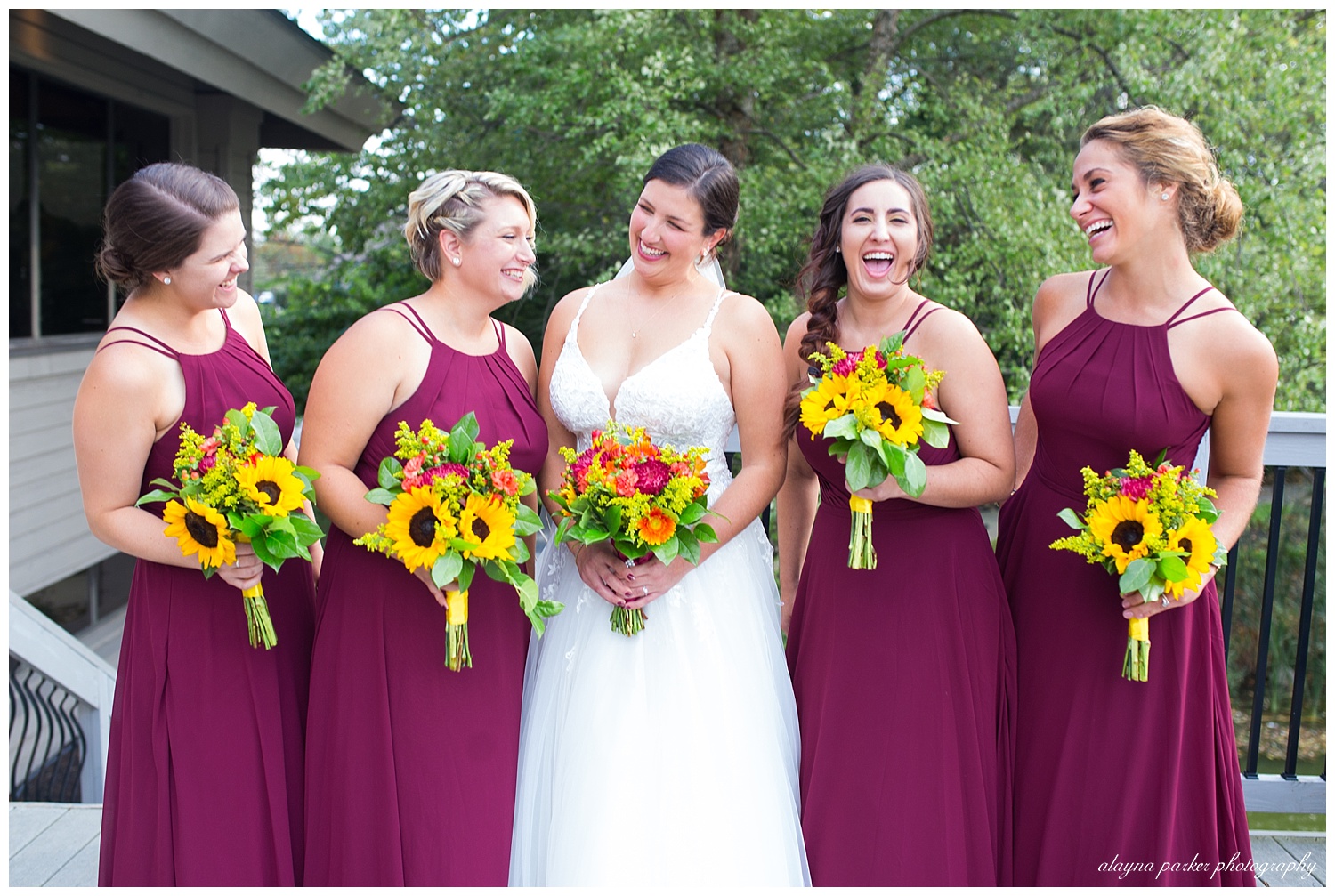 bride and bridesmaids laughing at each other outside at water's edge