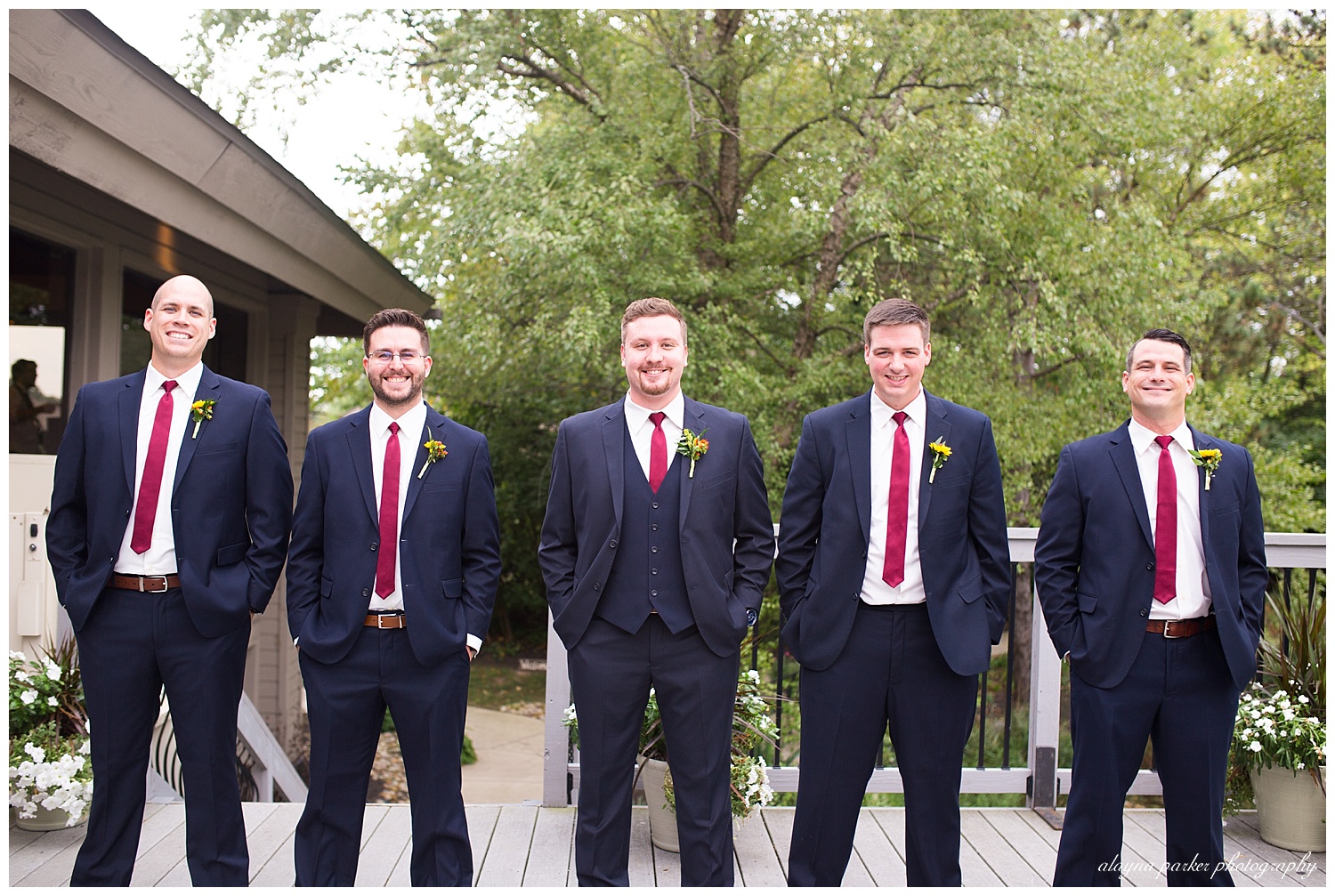 groom and groomsmen smiling at camera outside at water's edge