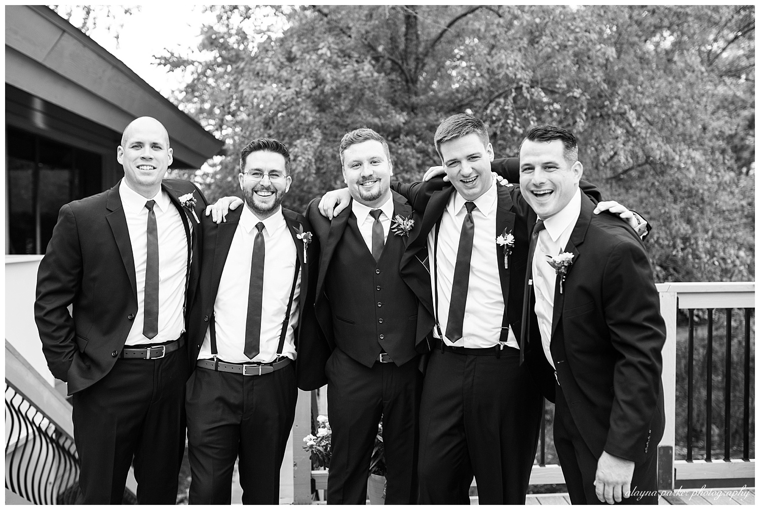 black and white image of groom and groomsmen hugging outside at water's edge