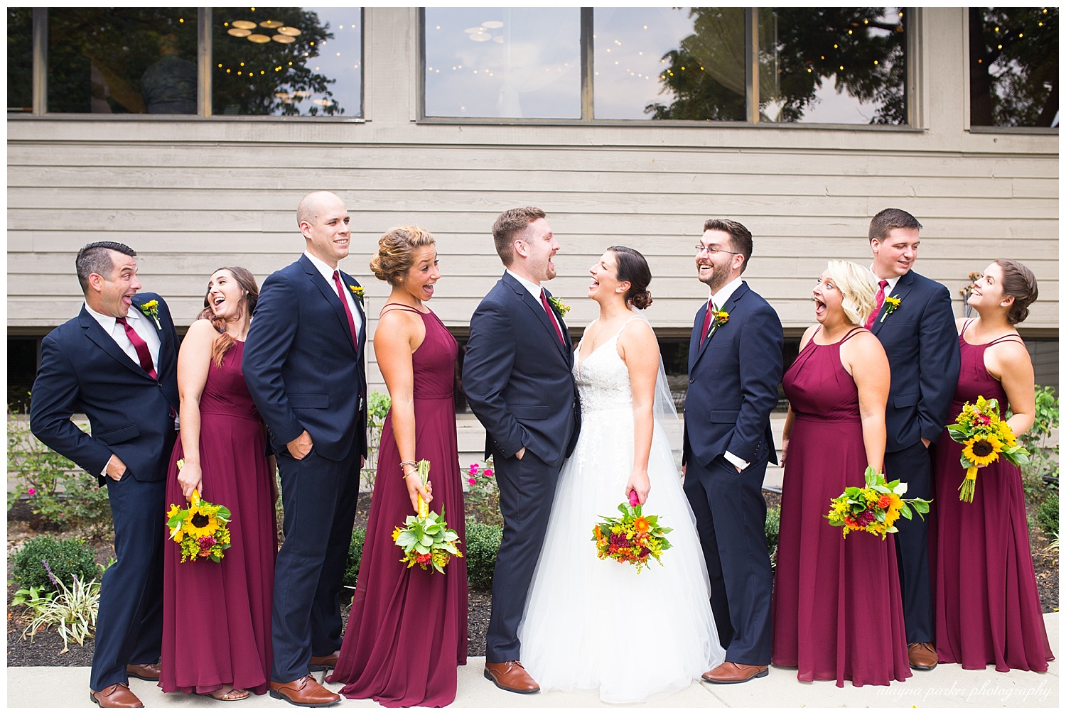 bridal party laughing at each other outside at water's edge
