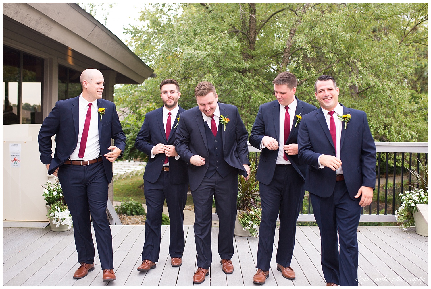 groom and groomsmen laughing and walking outside at water's edge