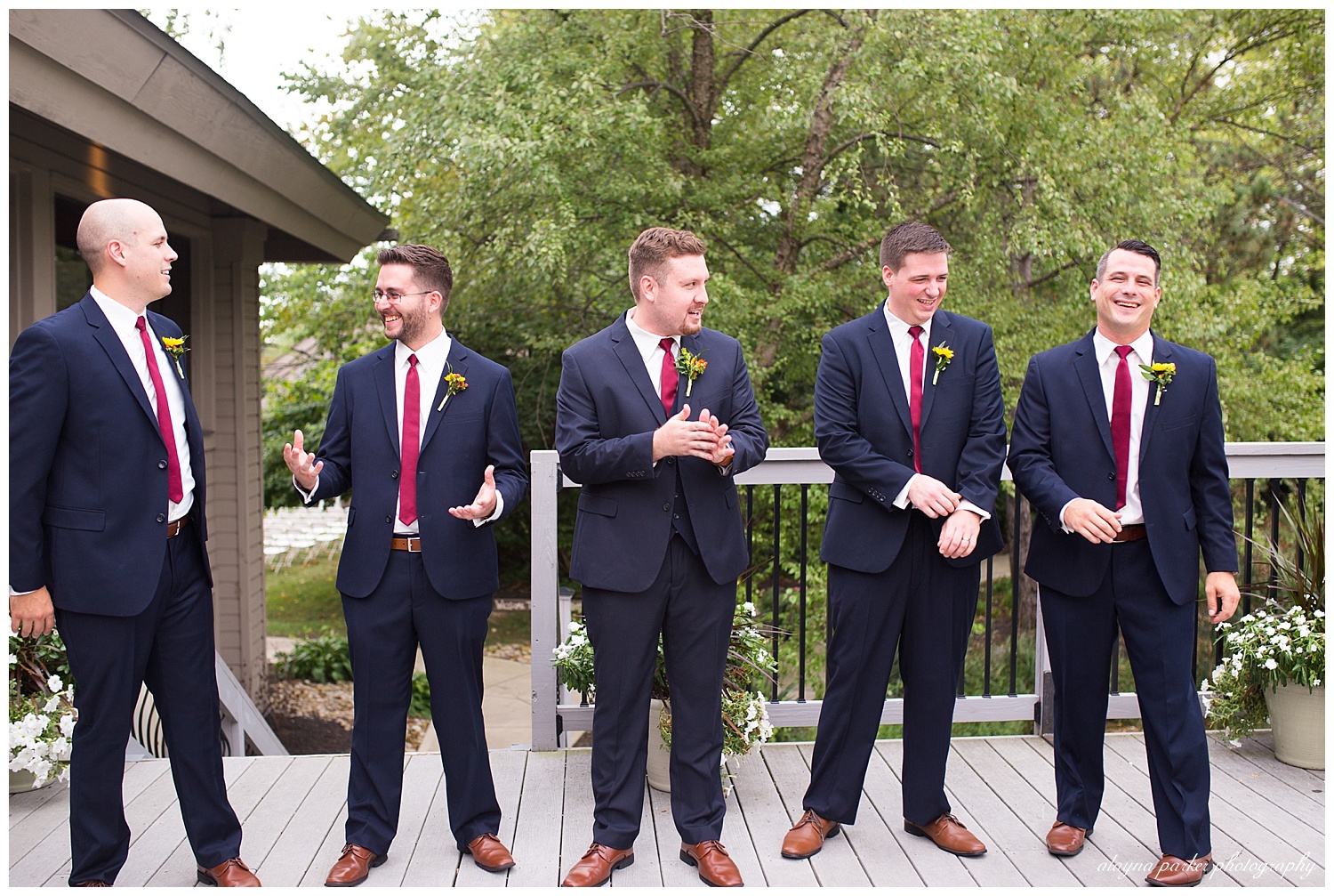 groom and groomsmen laughing outside at water's edge
