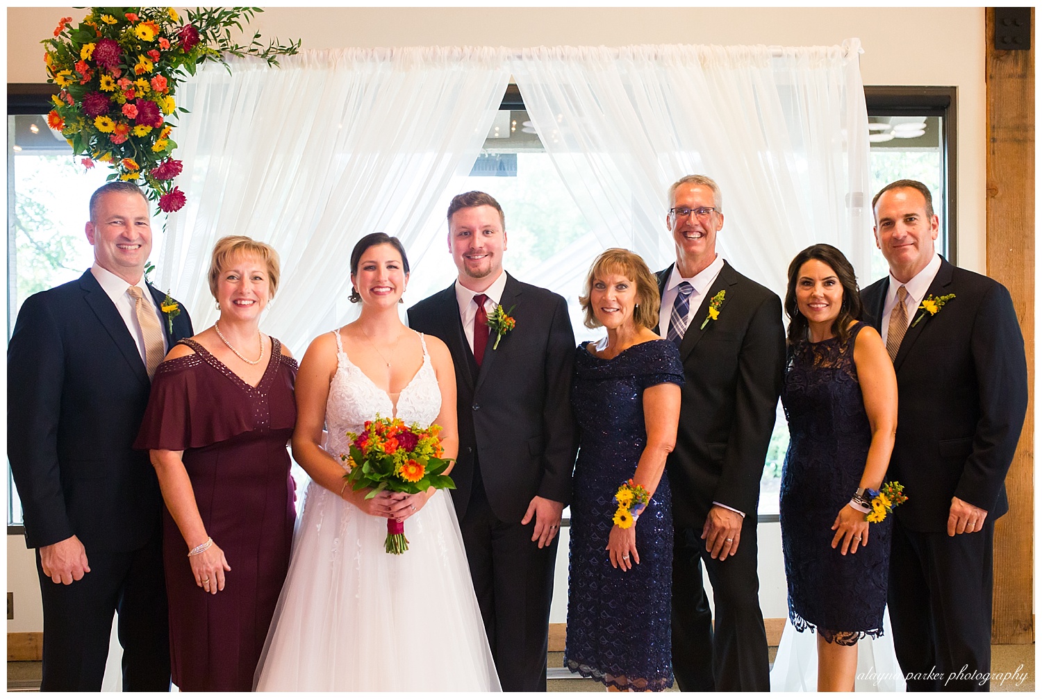 formal photo of bride and groom with parents at water's edge