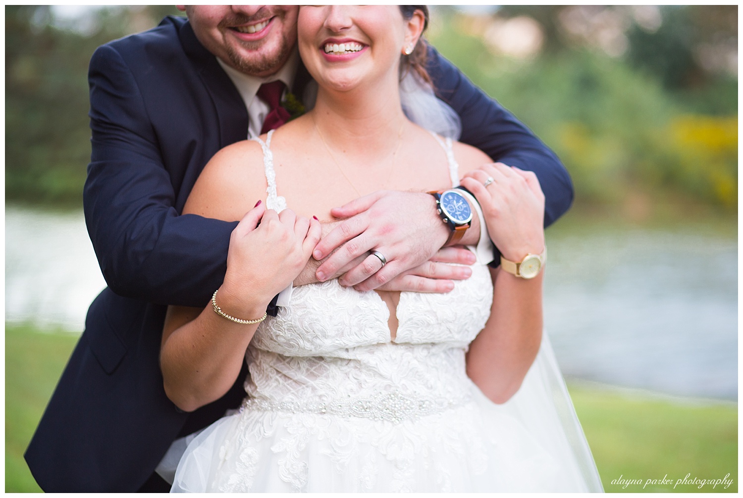 close up of groom holding on to bride at water's edge