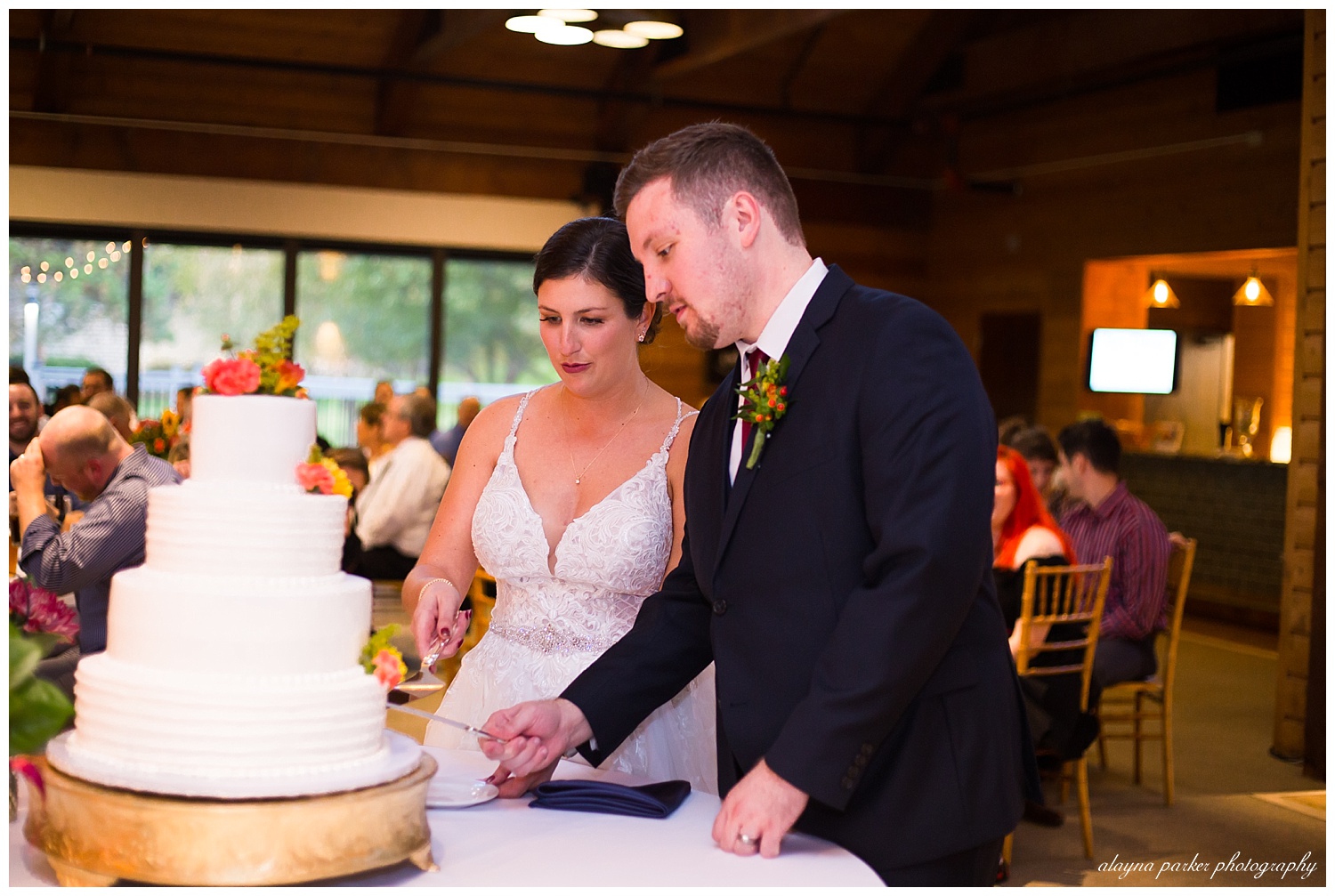 bride and groom cutting cake at water's edge