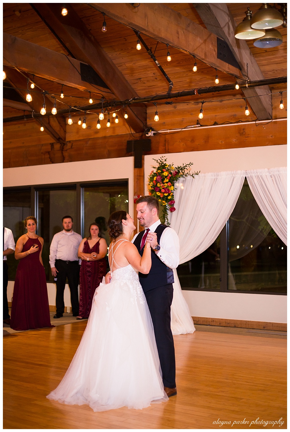 bride and groom smiling during first dance at water's edge