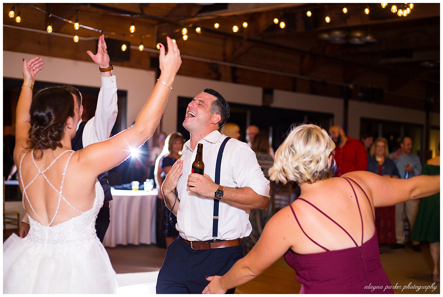 bride and brother dancing at water's edge
