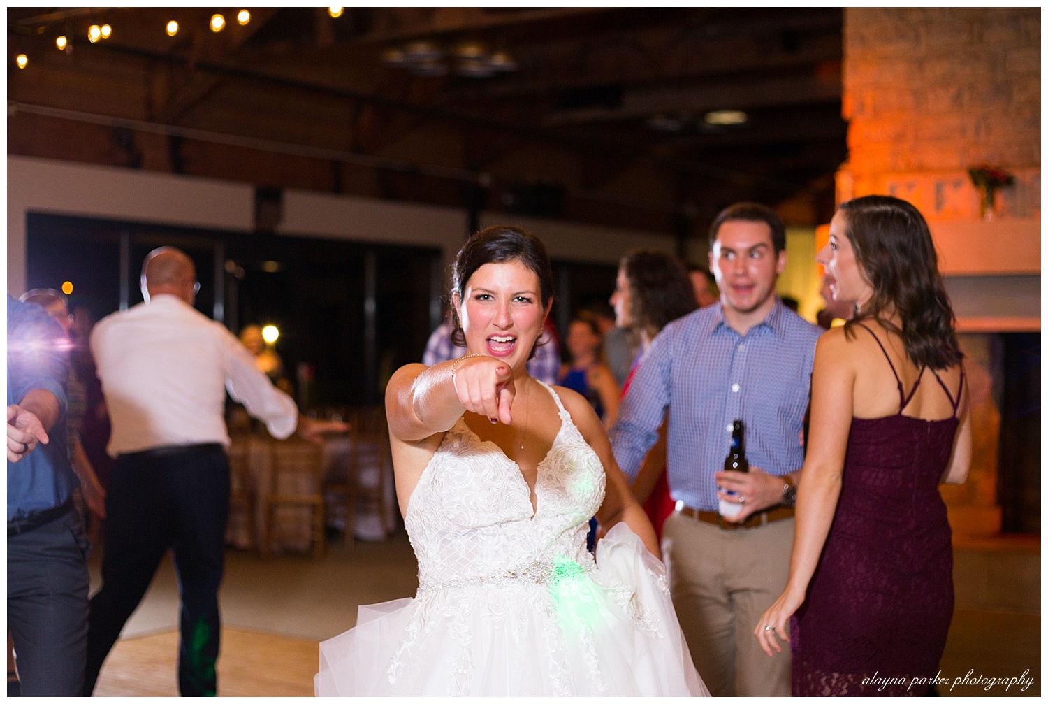 bride pointing at camera while dancing at water's edge