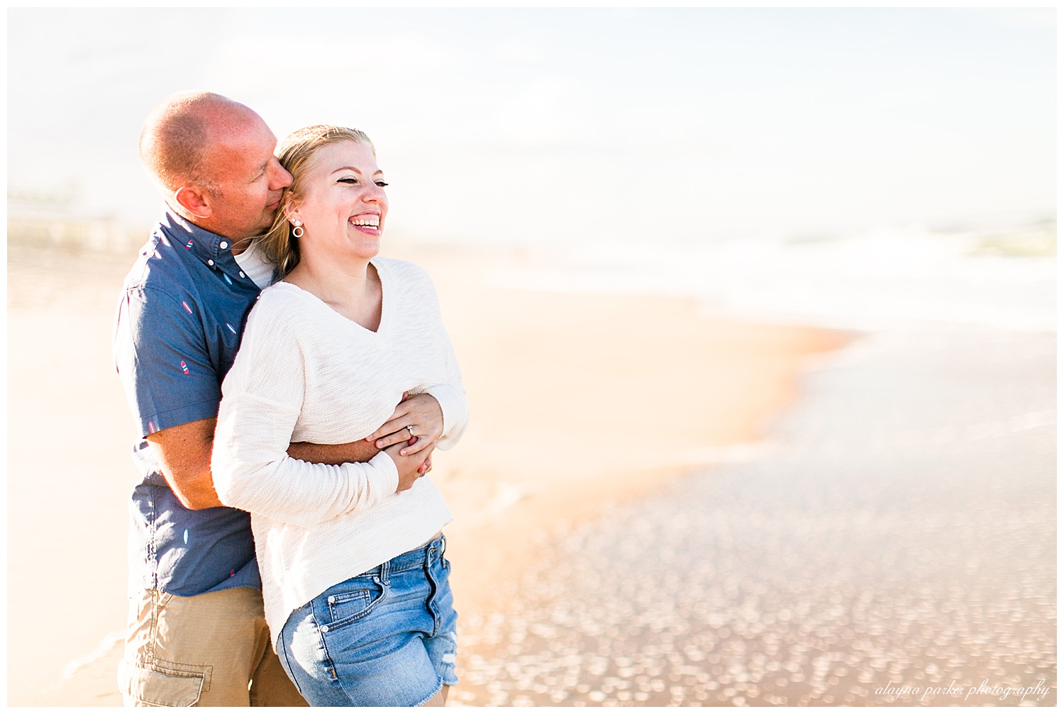 woman laughing while man hugs her on beach in outer banks