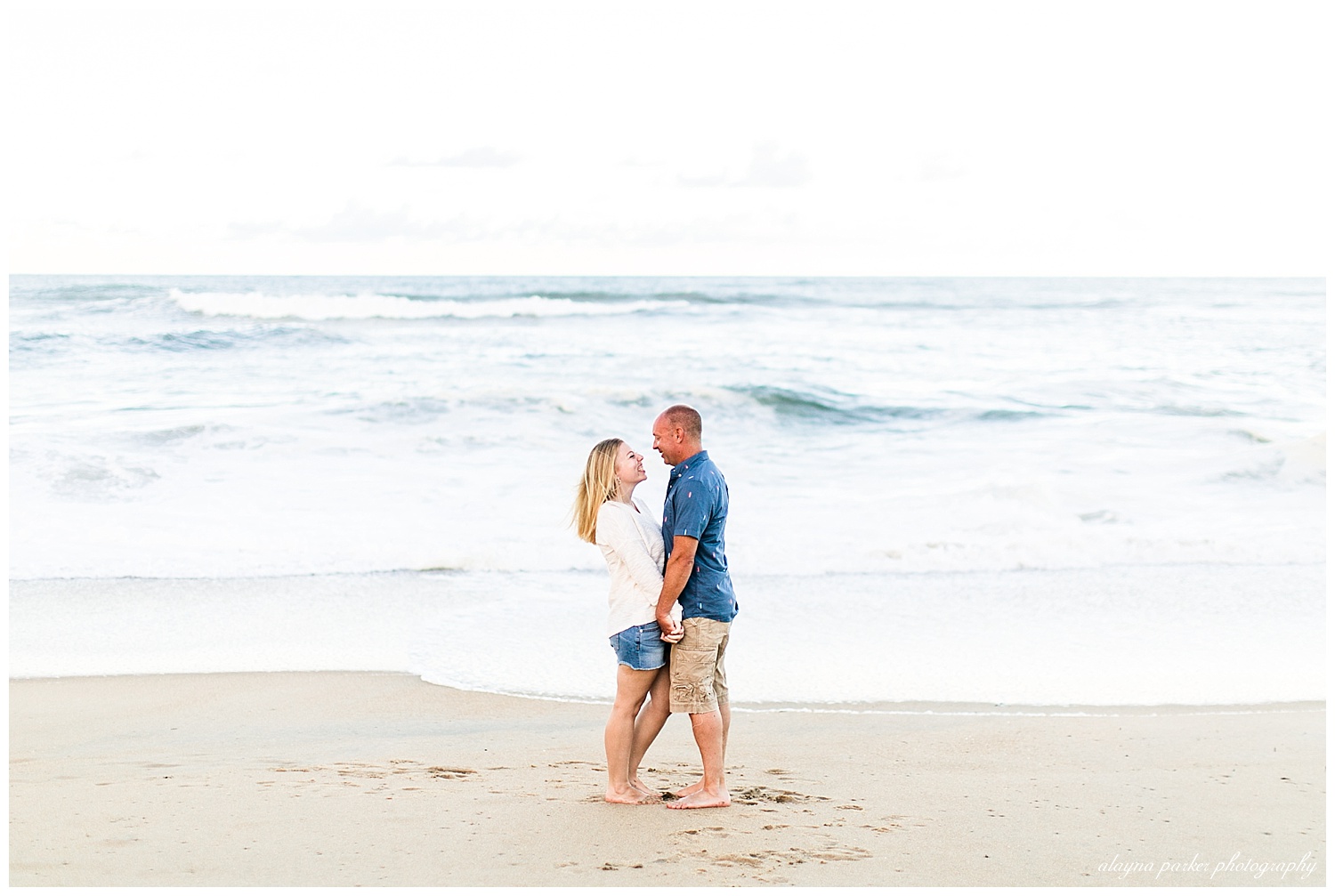 couple holding hands in front of water on beach in outer banks
