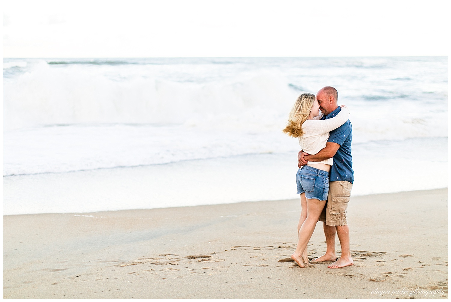 couple hugging in front of waves on beach in outer banks