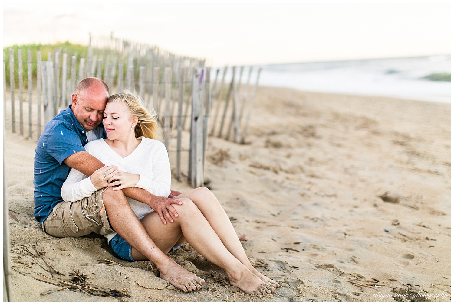 couple sitting by dunes on beach in outer banks