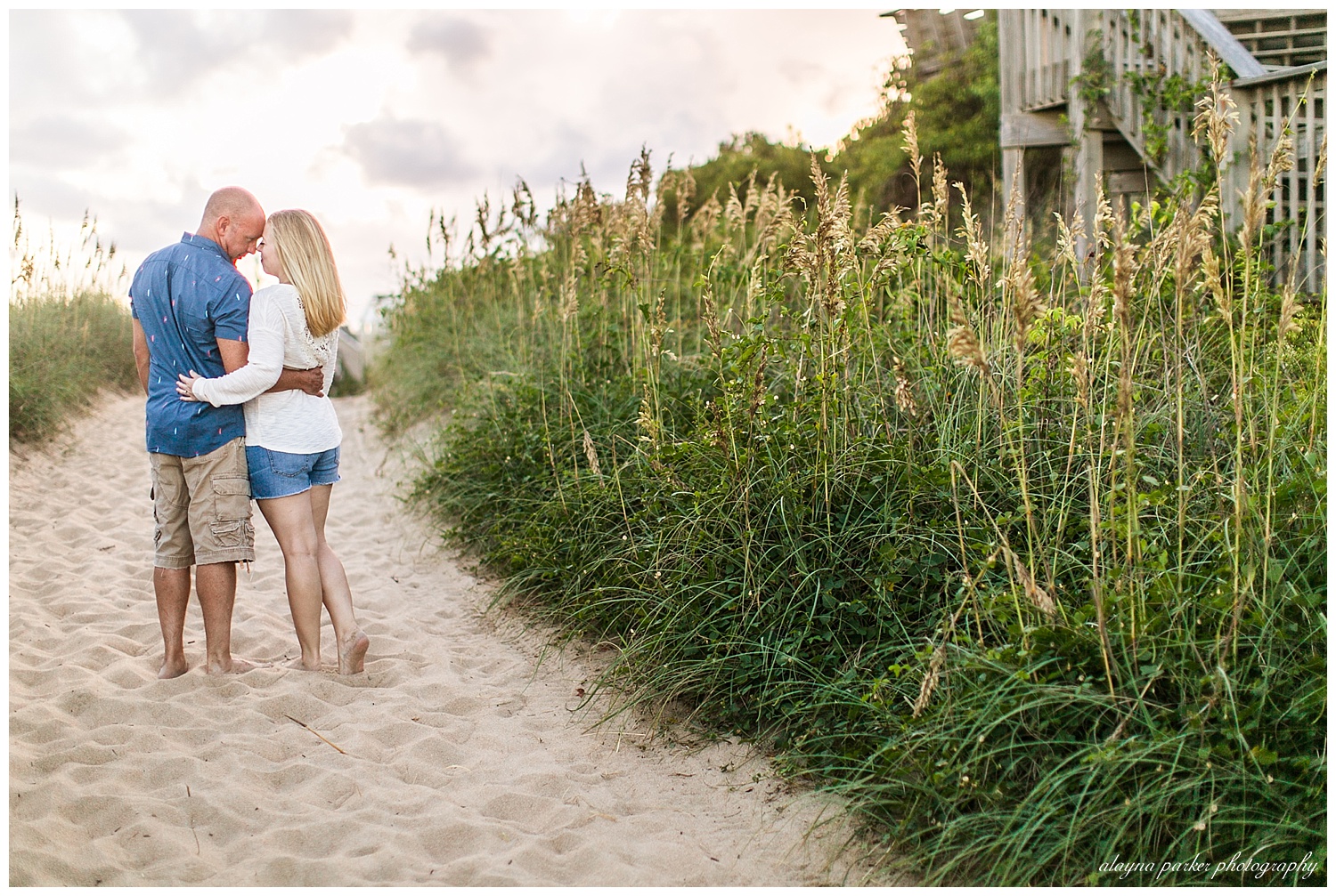 couple touching foreheads along path on beach in outer banks