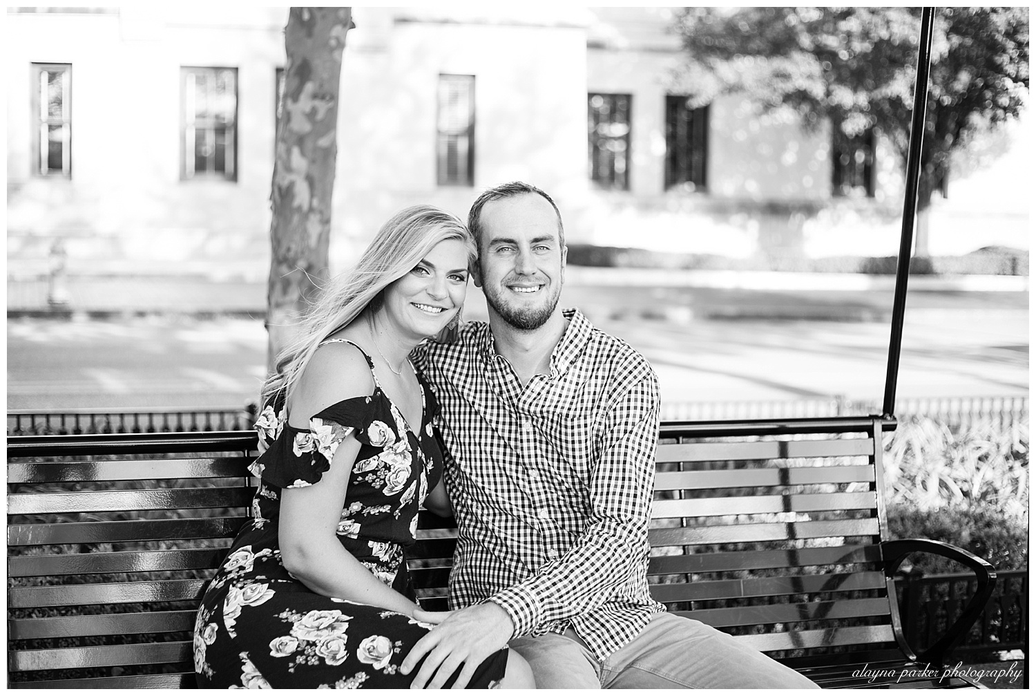 black and white image of couple sitting on bench and smiling at camera at scioto mile