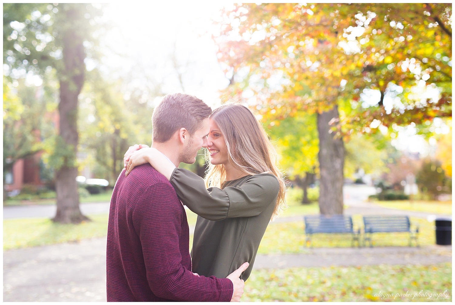 couple smiling at each other with sun shining behind them at schiller park in german village