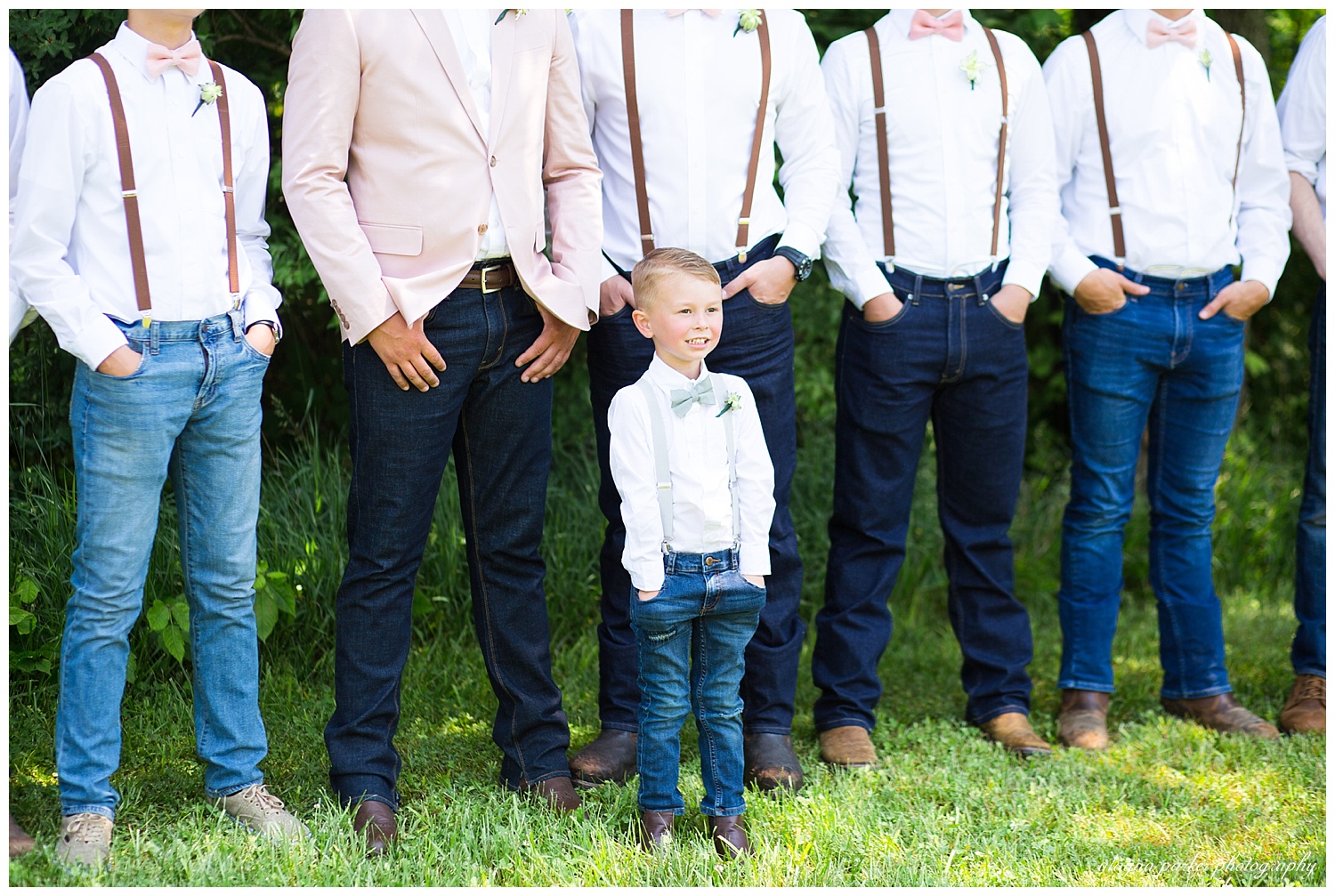 ring bearer in white tie, denim pants, and blue suspenders