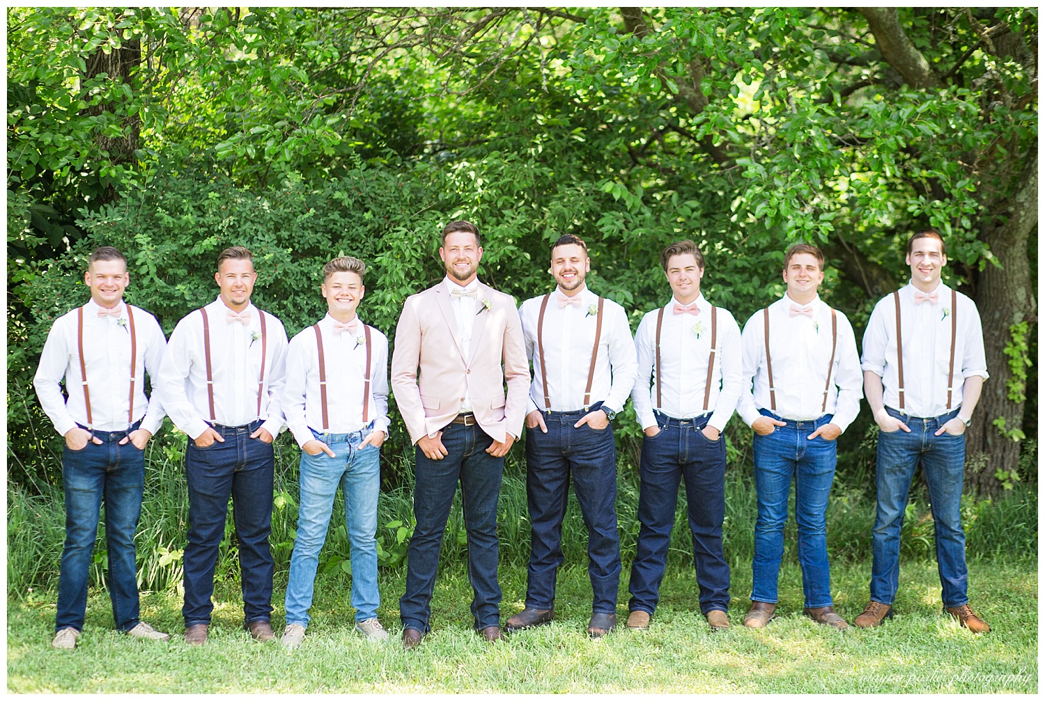 groomsmen wearing white shirt, denim jeans, brown suspenders, and pink bowtie