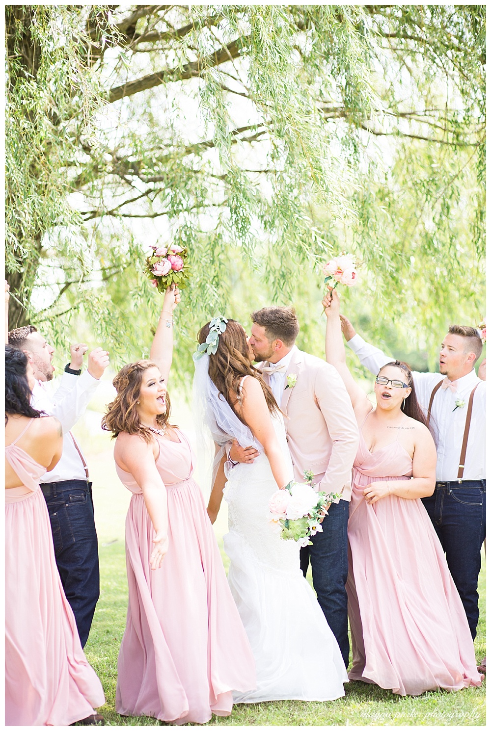bridal party cheering as bride and groom kiss