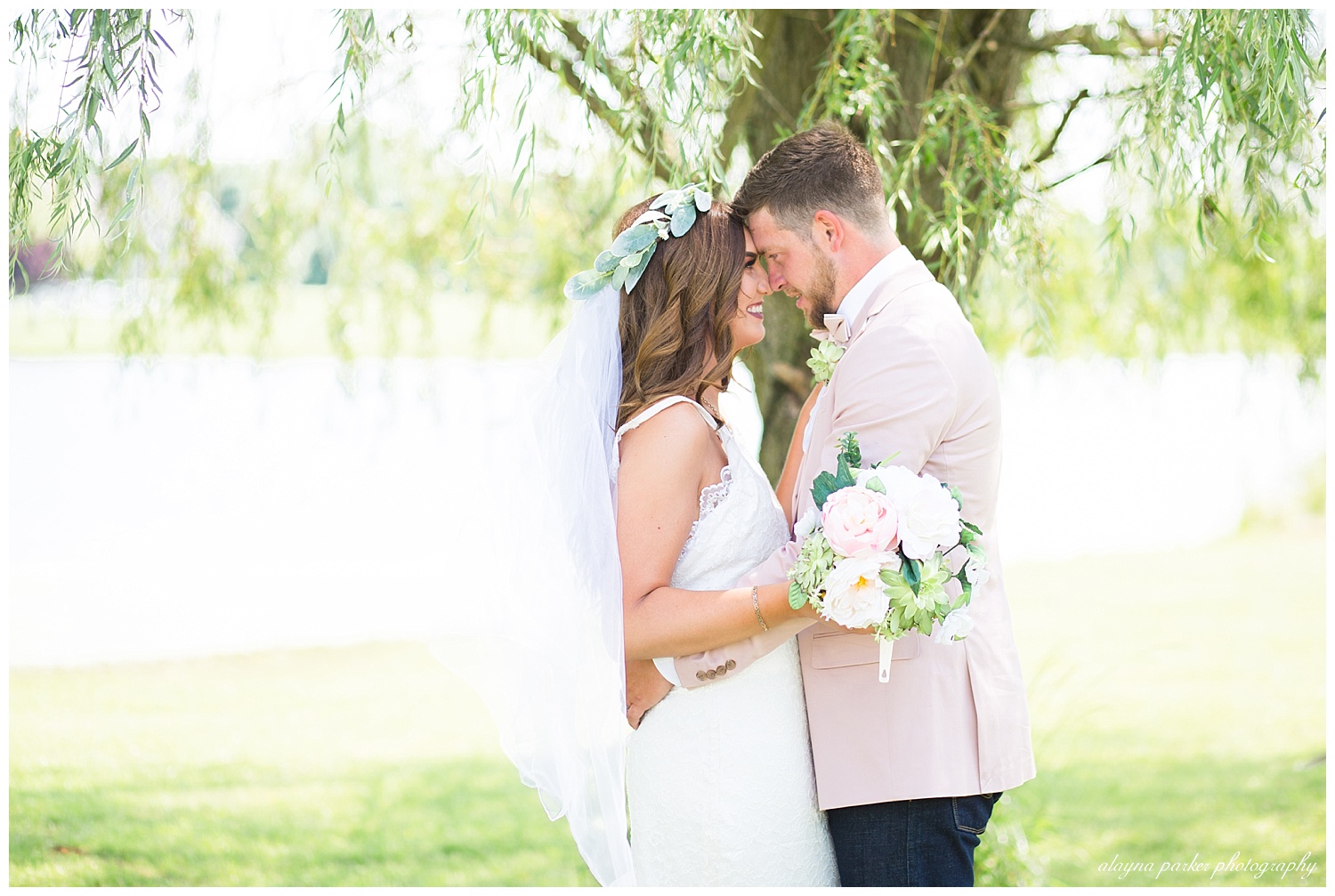 bride and groom touching foreheads under willow tree