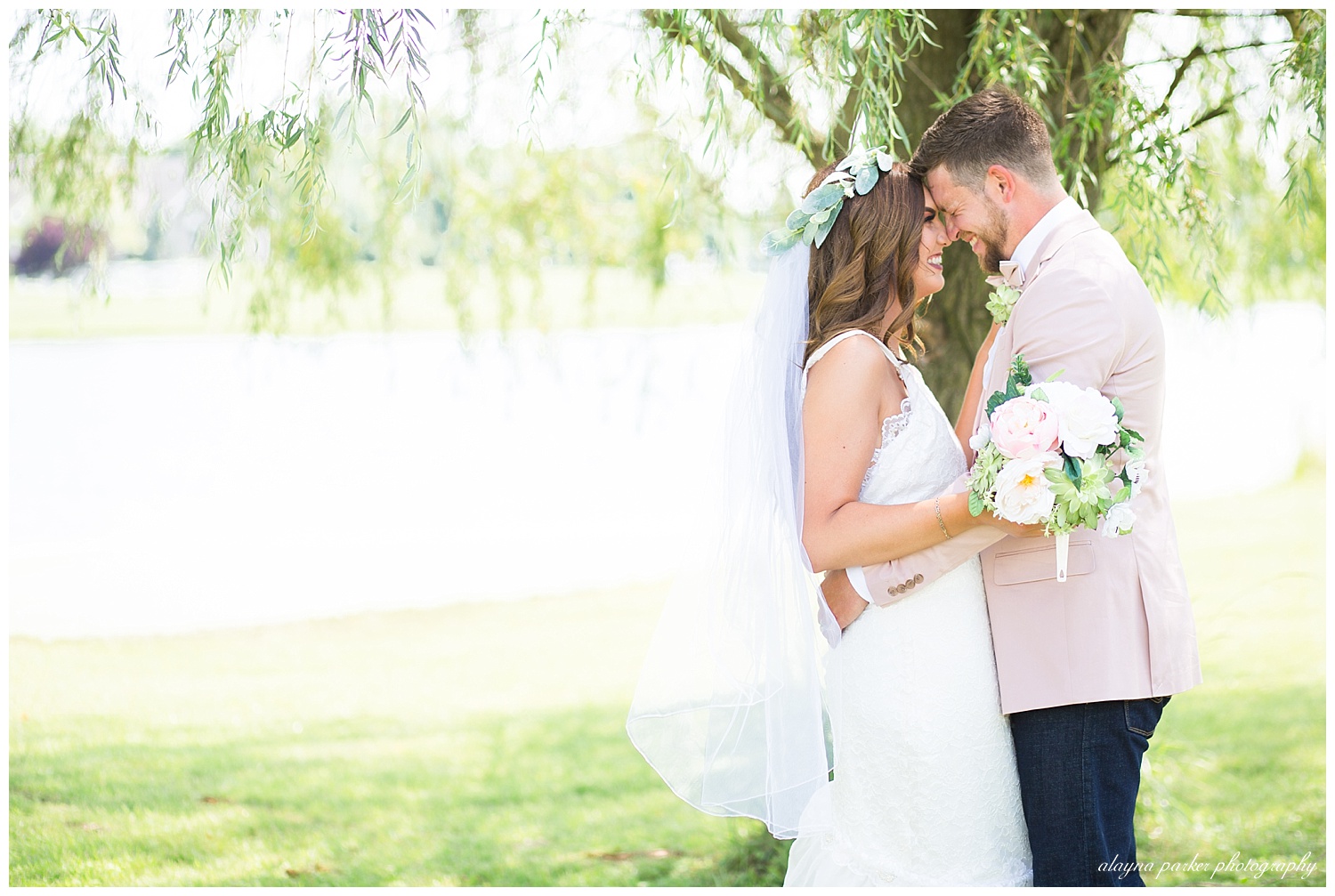 bride and groom laughing underneath willow tree