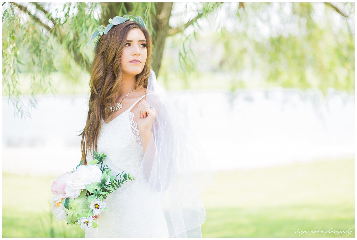 bride holding veil and looking over shoulder under willow tree