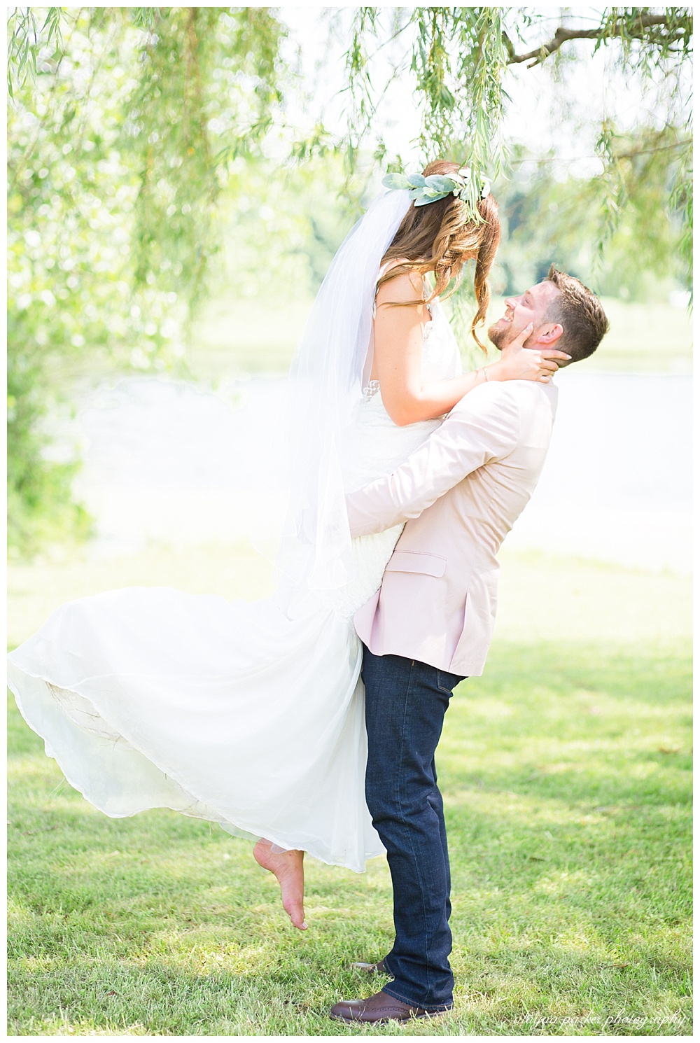 groom picking up bride under willow tree