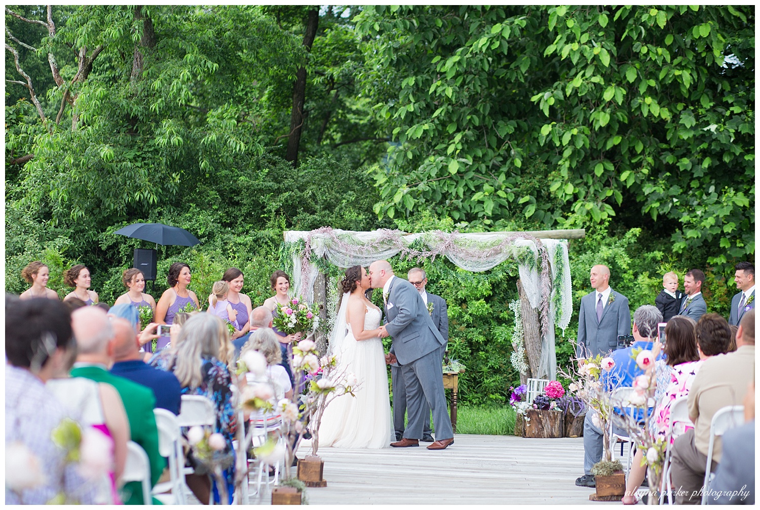 bride and groom have first kiss at the barn on enchanted acres