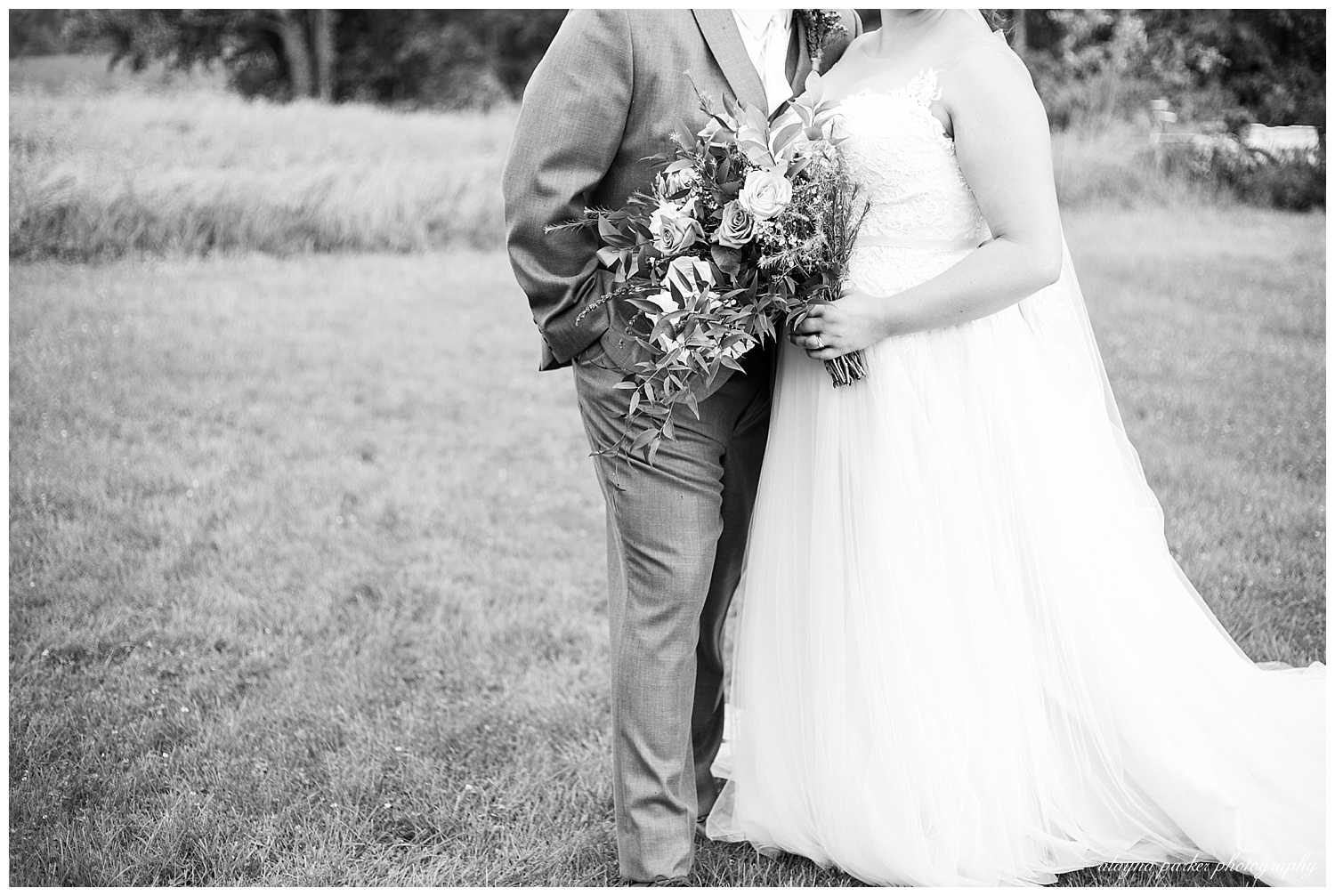 black and white image of bride holding her bouquet and groom with hand in pocket