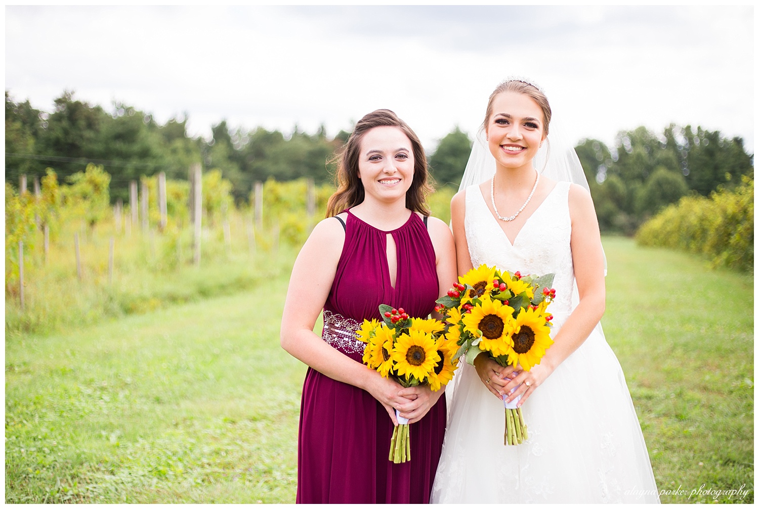 bridesmaid wearing merlot colored dress and holding a sunflower bouquet