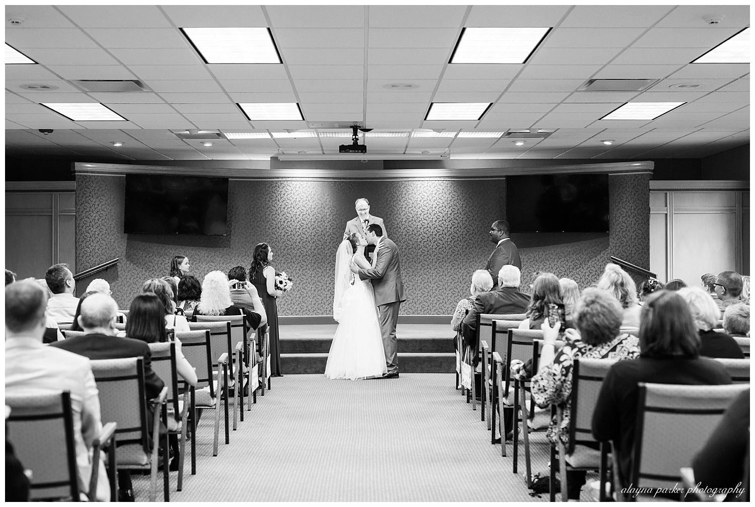 black and white image of bride and groom sharing first kiss