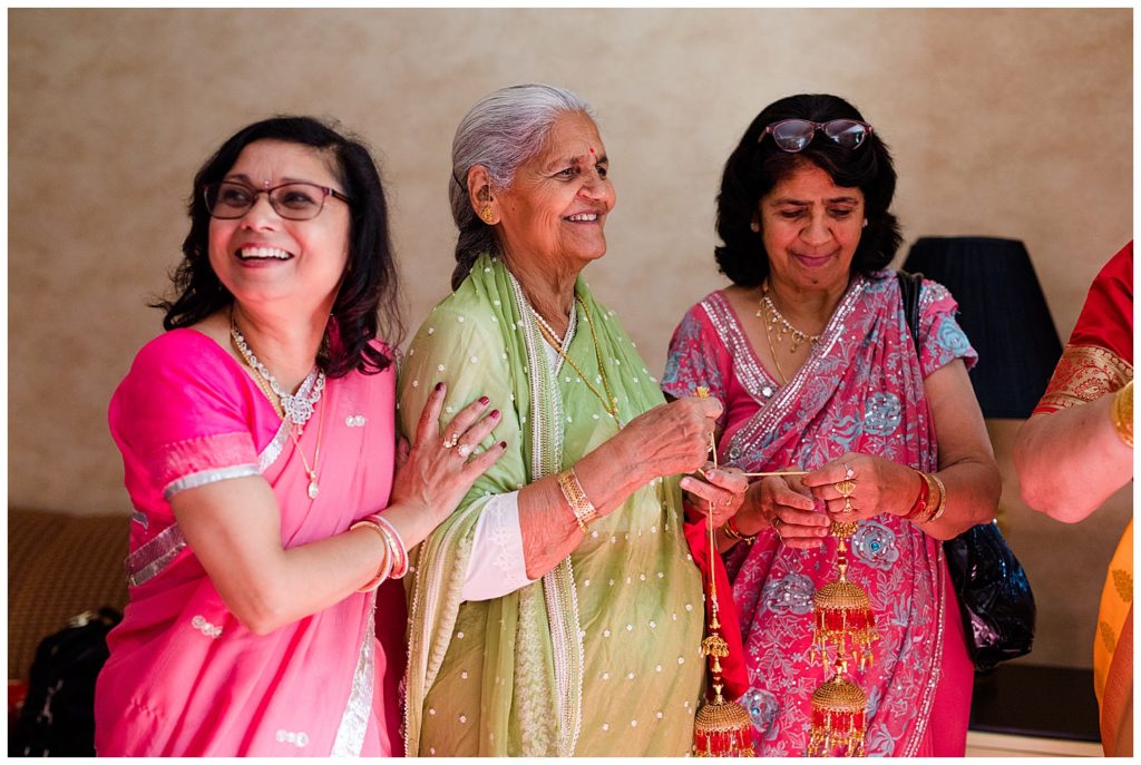 older indian women helping bride get dressed