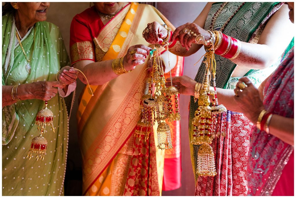 older indian women helping bride get dressed