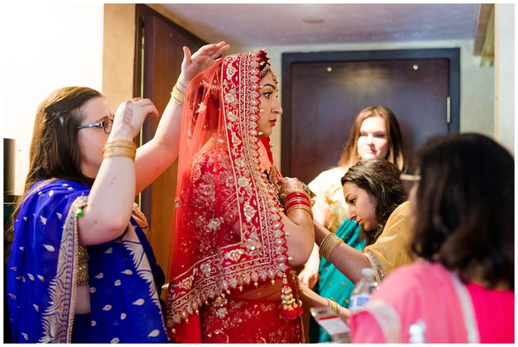 bride getting dressed in wedding saree