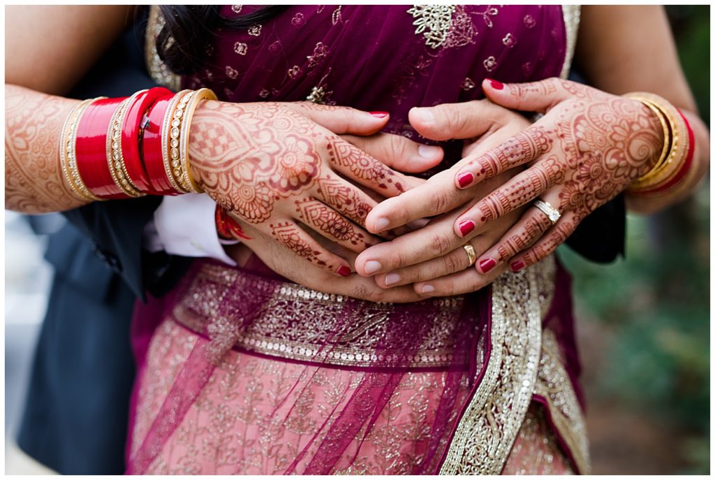 close up of bride and groom's rings with henna tattoos