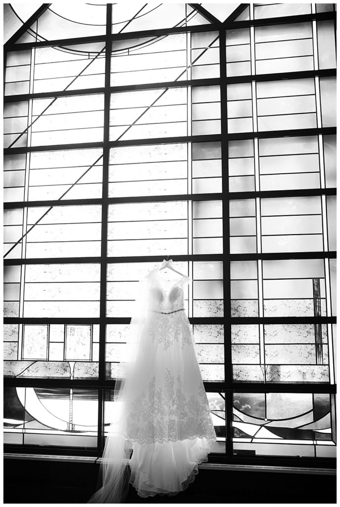 black and white image of wedding dress hanging on stained glass windows