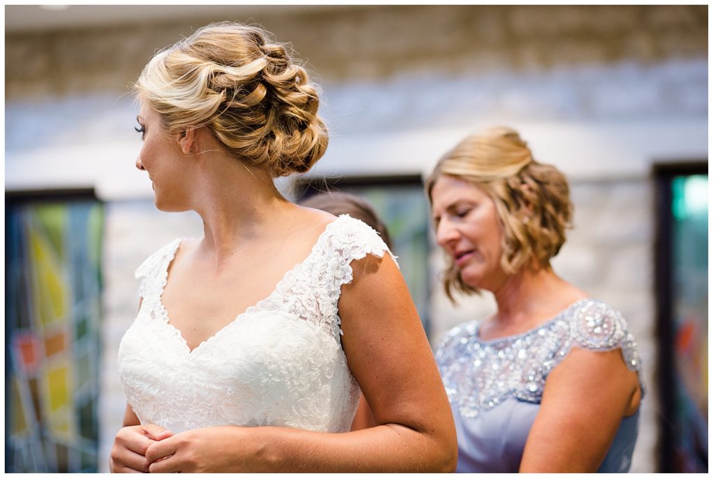 bride turning her head as she gets wedding dress on