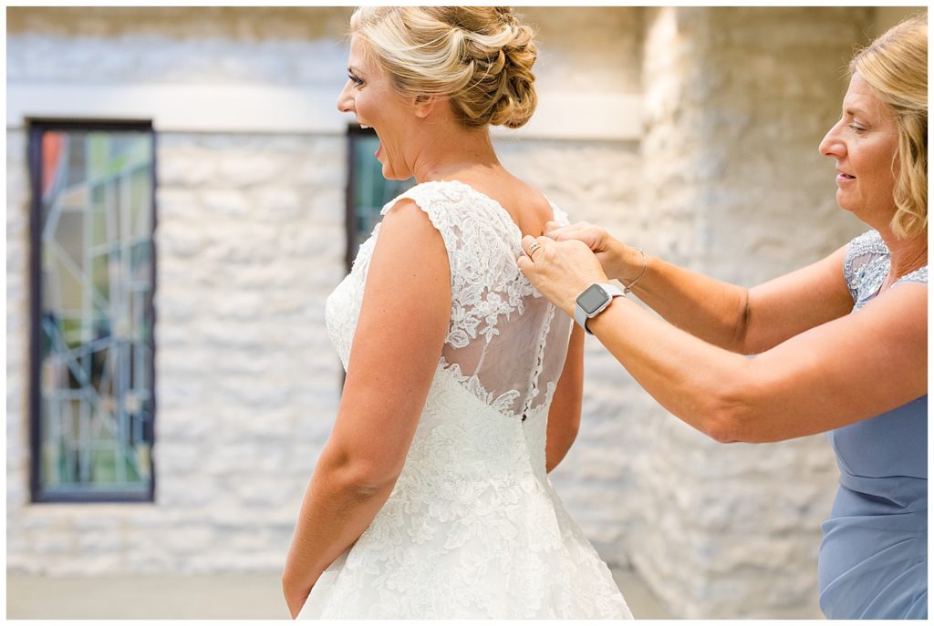 bride laughing with excitement as her wedding dress is buttoned
