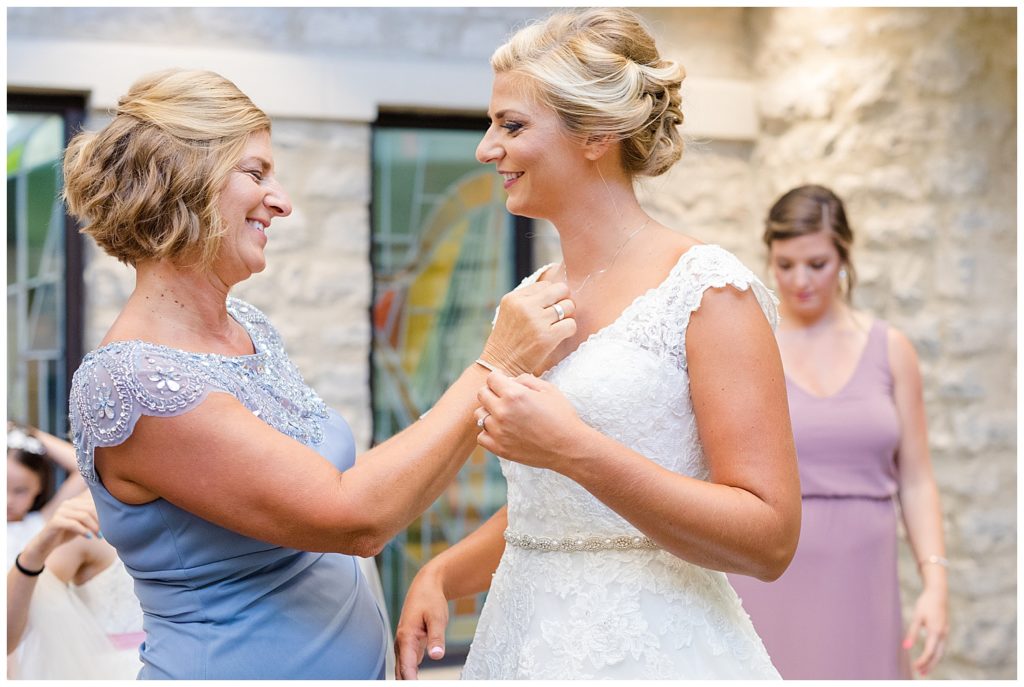 mother putting bride's necklace on