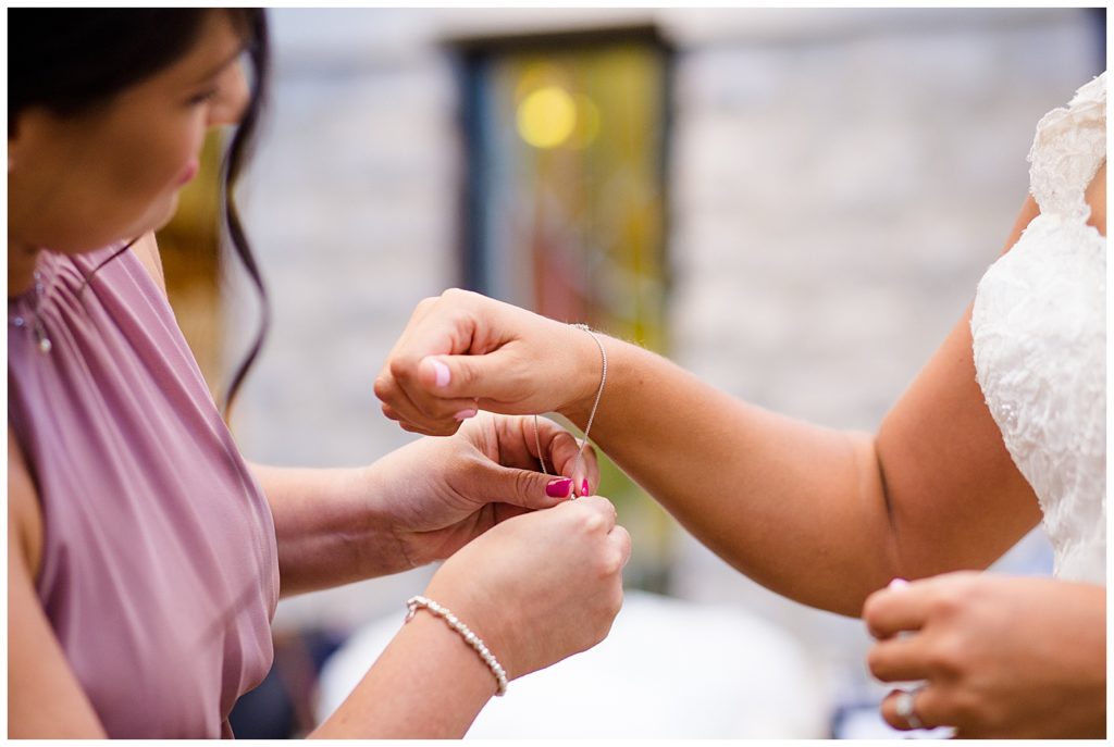 bridesmaid helping bride put bracelet on