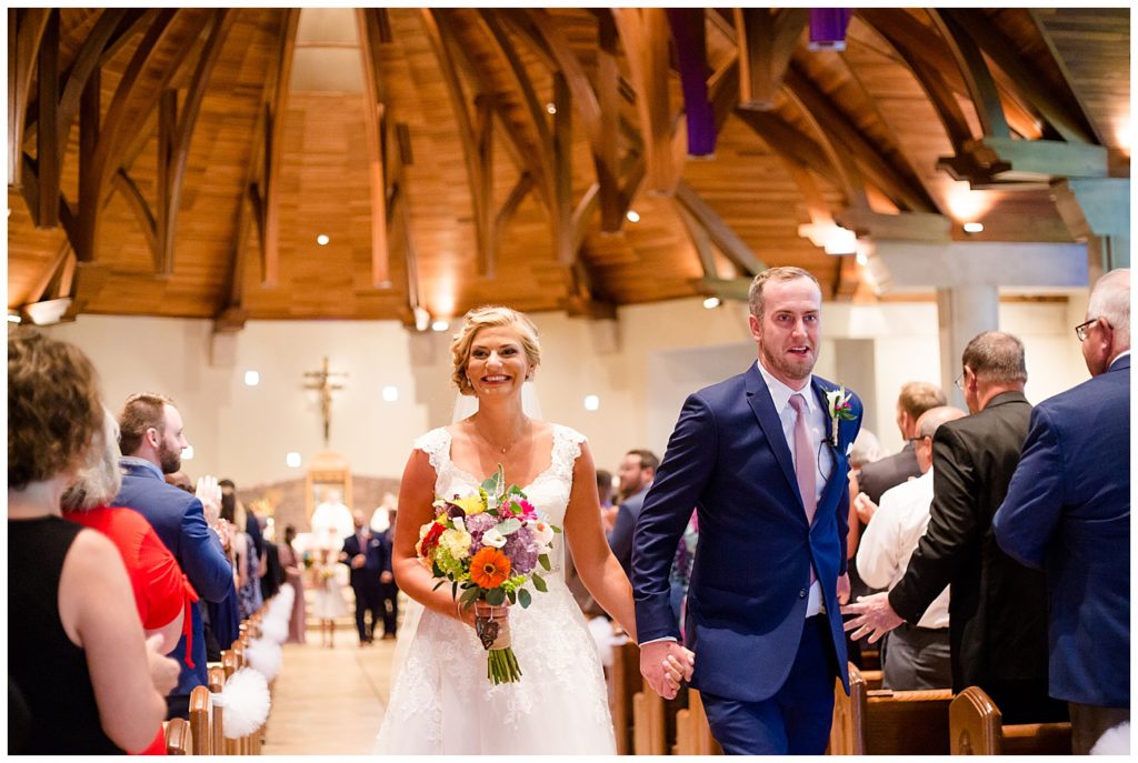 bride and groom smiling as they walk up the aisle after ceremony