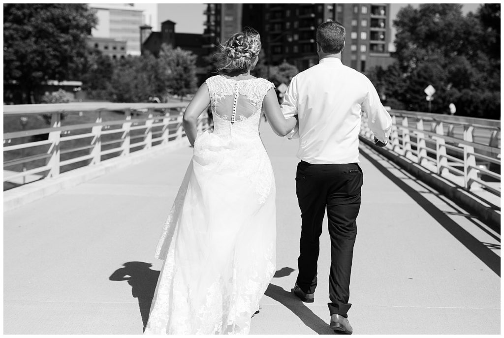 black and white image of bride and groom walking on washington st bridge